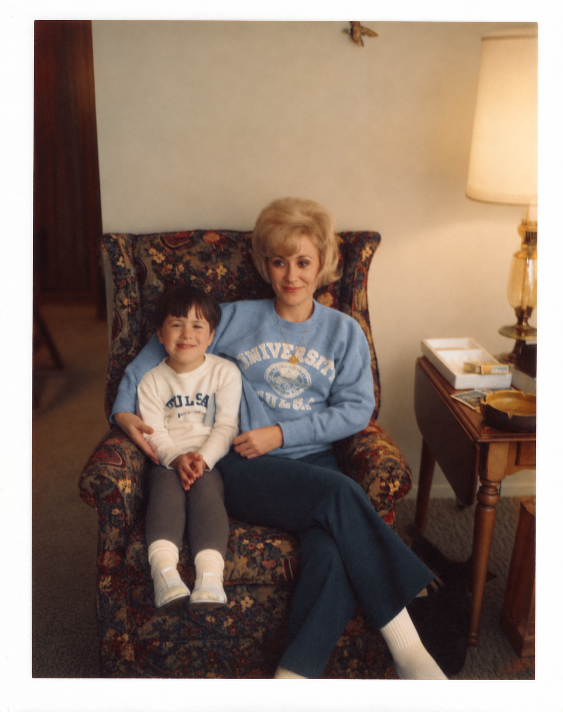 Gia as a child sitting with her mother, Ivana Sue Birdwell Anderson, in a patterned armchair