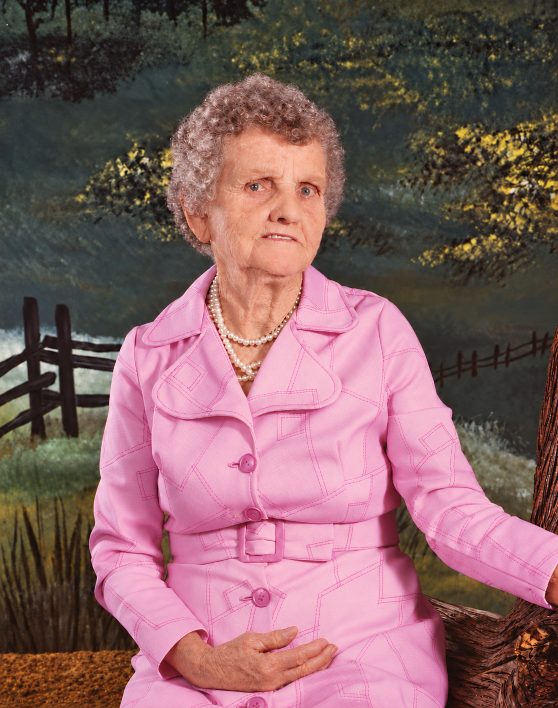 Julia Mae Riddle Perry seated in a pink suit and pearl necklace