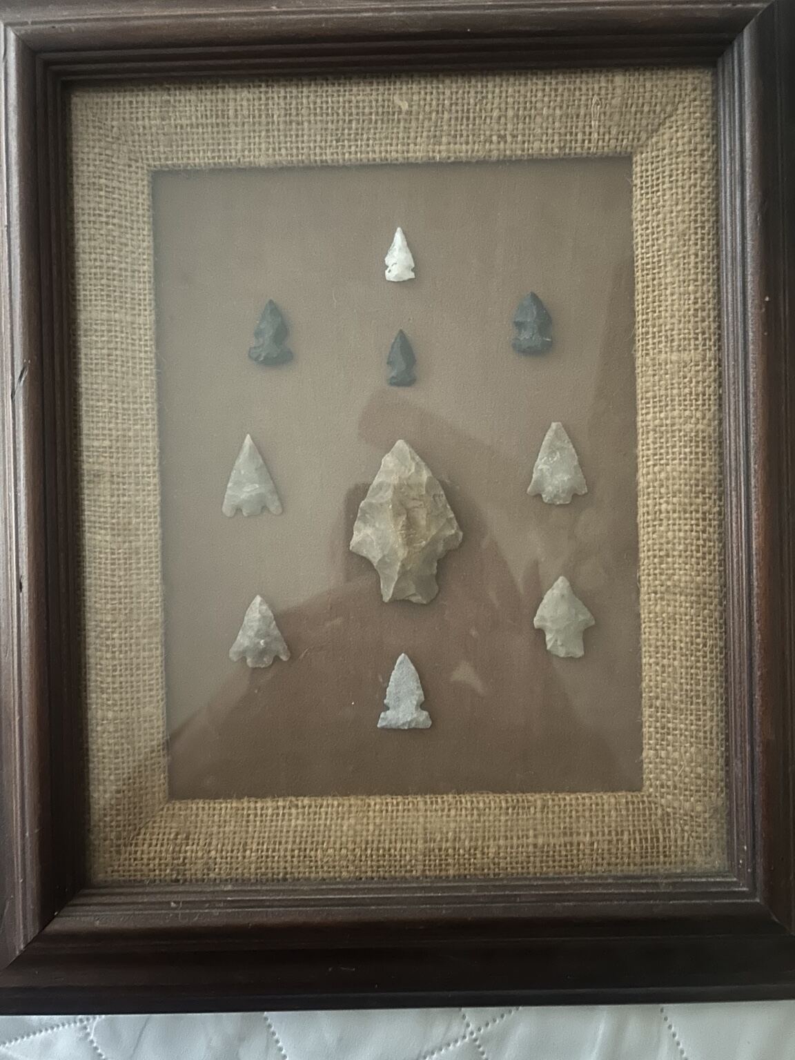 Nine worked-stone points arranged in a framed family display