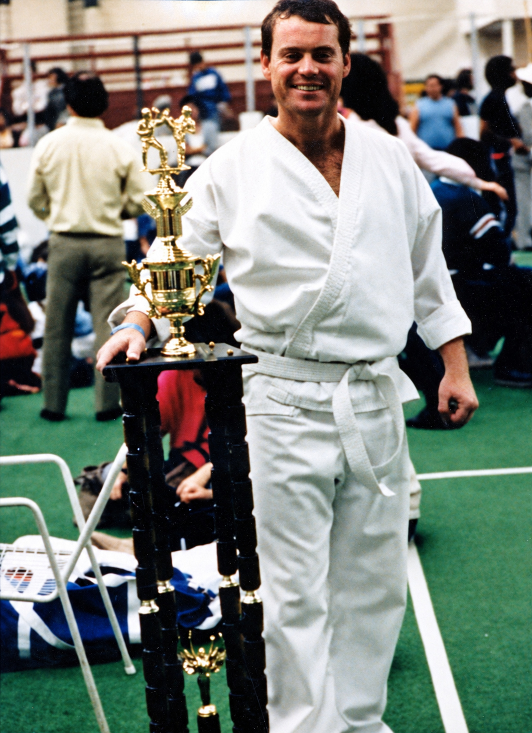 Perry Wayne Hollingsworth in a white karate gi beside a tall trophy