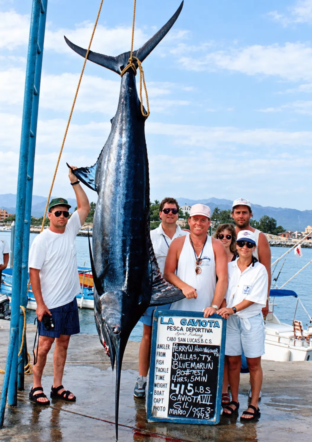 Family group beside a suspended blue marlin and fishing-board sign